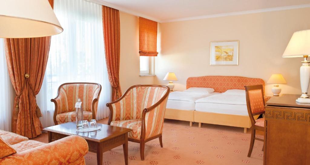 a hotel room with a bed and a table and chairs at Victor's Residenz-Hotel Erfurt in Erfurt