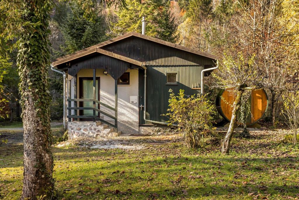 ein kleines grünes Gebäude auf einem Feld mit Bäumen in der Unterkunft Cabin by the river with Sauna in Polhov Gradec