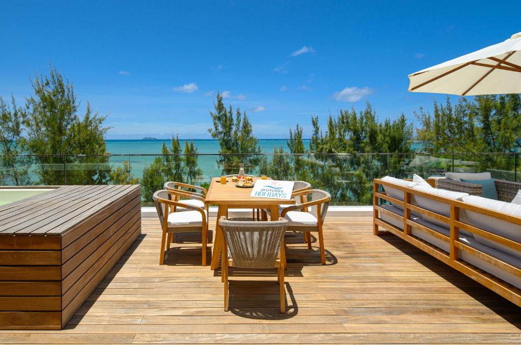 a deck with a table and chairs and a view of the ocean at Ocean Grand Gaube by 2futures Holidays in Grand Gaube
