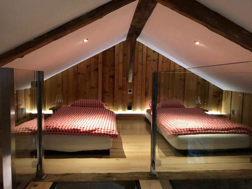 two beds in a room with wooden walls at BnB Le Mazot Fionnay in Fionnay
