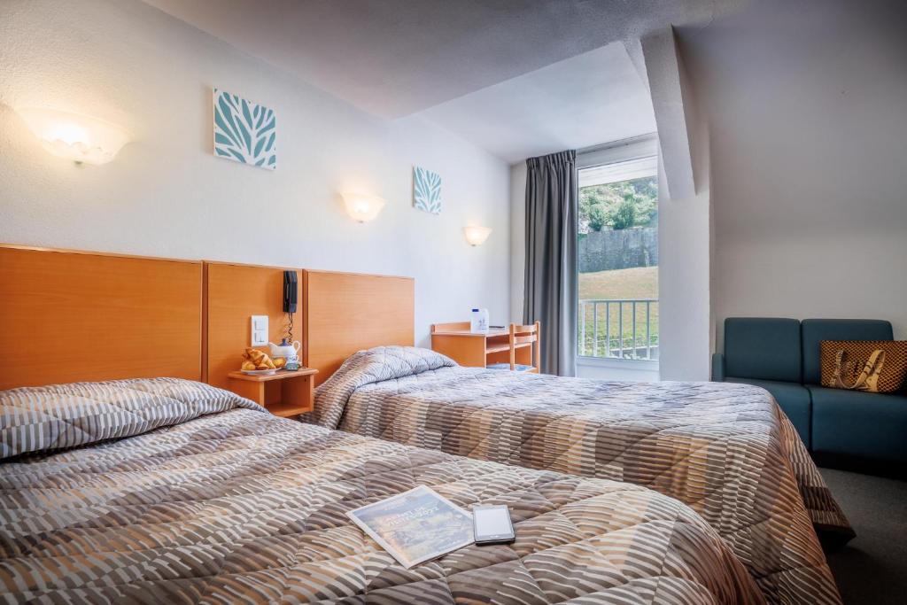 ルルドにあるHôtel Compostelleのベッド2台と窓が備わるホテルルームです。