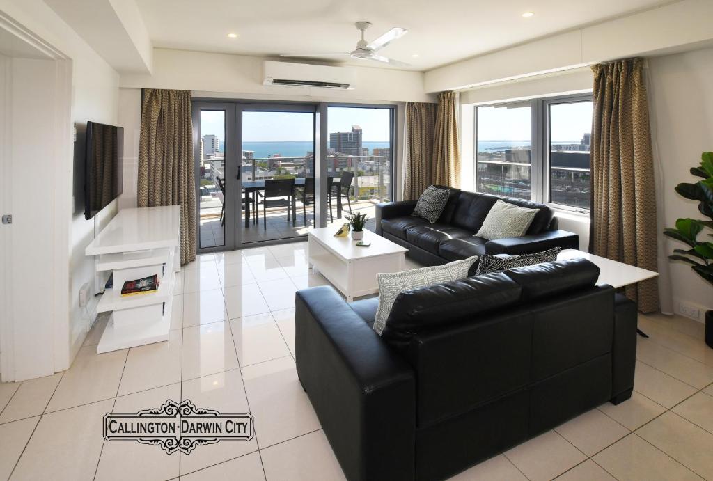 een woonkamer met zwart meubilair en een groot raam bij “CALLINGTON” Darwin City @PenthousePads in Darwin