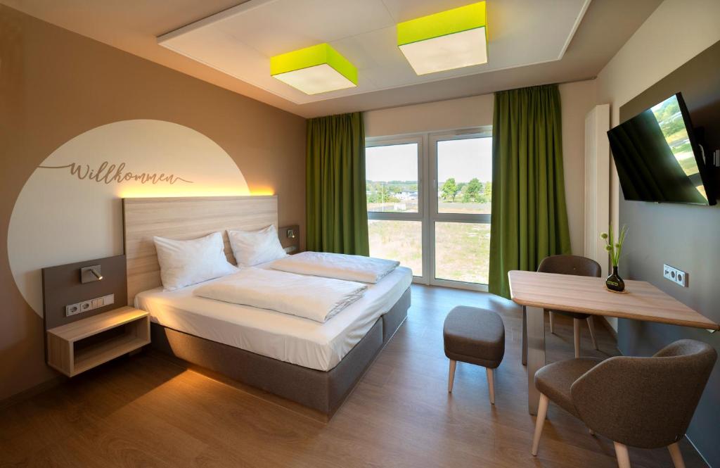 Dormitorio con cama, escritorio y TV en Mainfranken Motel - Anreise rund um die Uhr - Neueröffnung 2023, 