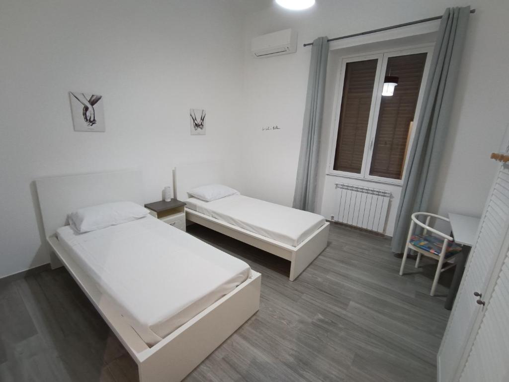 Dieses weiße Zimmer verfügt über 2 Betten und ein Fenster. in der Unterkunft Tati's Garden in Palermo