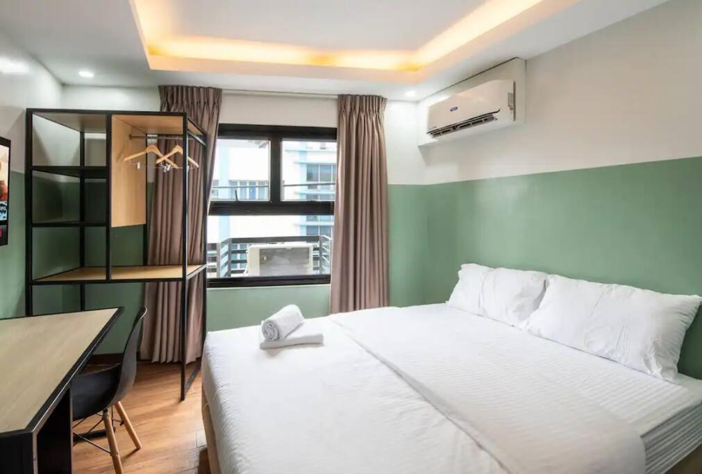 1 dormitorio con cama, escritorio y ventana en St. Marvin Studio Makati M503, en Manila