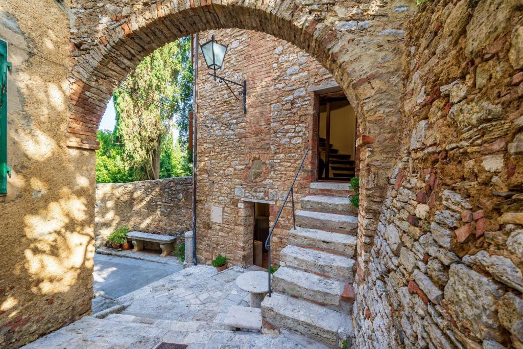 une arche dans un bâtiment en pierre avec des escaliers dans l'établissement Torre Di Serre by PosarelliVillas, à Serre di Rapolano