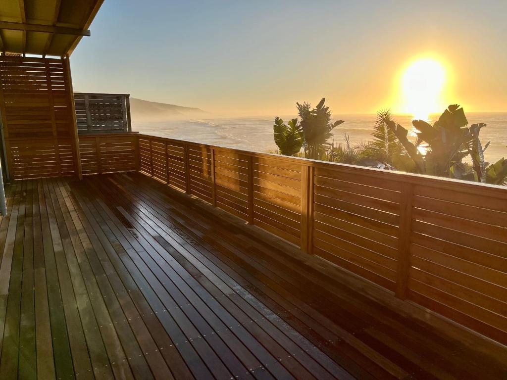 a wooden deck with the sunset in the background at Mitford The N I C E Condo in Morganʼs Bay