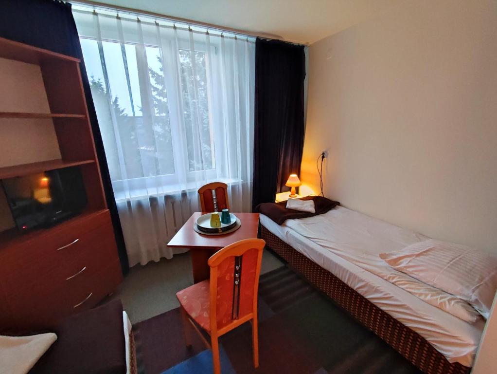 a bedroom with a bed and a table and a window at Płonia Economy in Szczecin