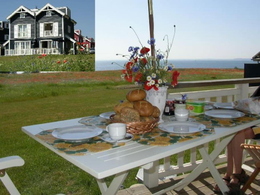 a picnic table with plates of food and a vase of flowers at Ferienhaus Meerblick in Sierksdorf