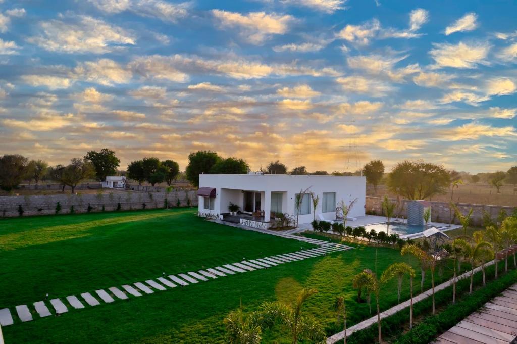 uma villa com um relvado verde em frente a um edifício em The Peace- A Luxury Pool Villa em Jaipur
