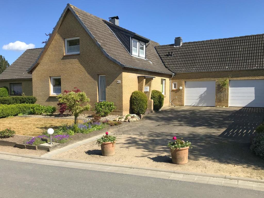 a house with two potted plants in the driveway at Husly Gondesen in Sörup