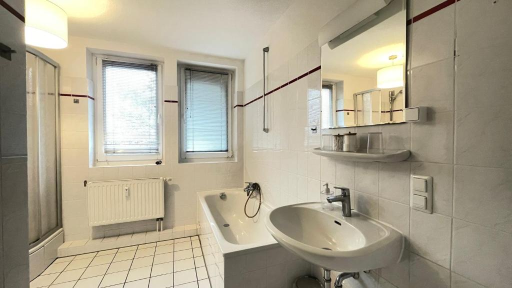 a white bathroom with a sink and a tub at Air Apartments 9 in Bremen