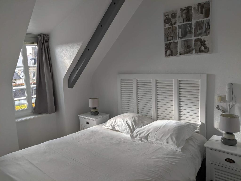 Contact Hôtel - Hôtel Le Lion d'Or Lamballe في لومبال: غرفة نوم بيضاء بها سرير ونافذة