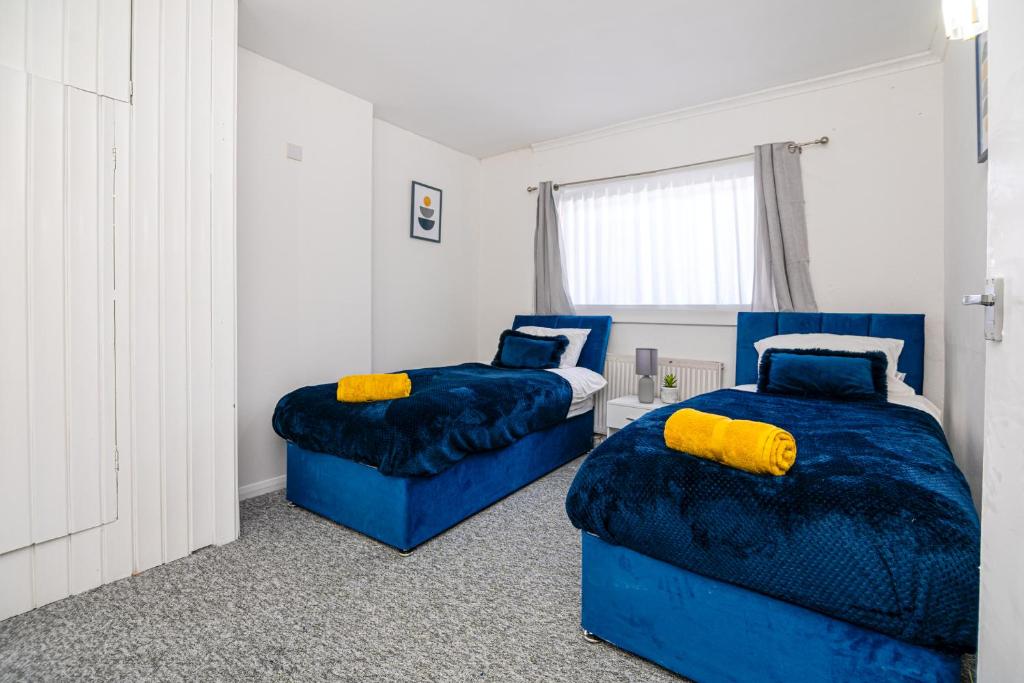 1 Schlafzimmer mit 2 blauen Betten und einem Fenster in der Unterkunft Impeccable 3-Bed House in Abbeywood in London