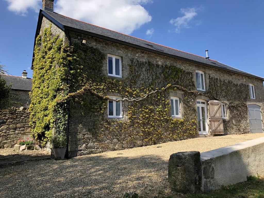 an old stone building with ivy growing on it at Dishcombe Cottage in Okehampton