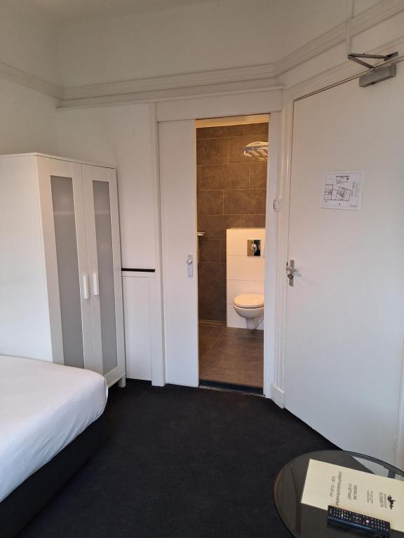 a room with a bed and a bathroom with a toilet at Stad &amp; Strandhotel Elisabeth in Vlissingen