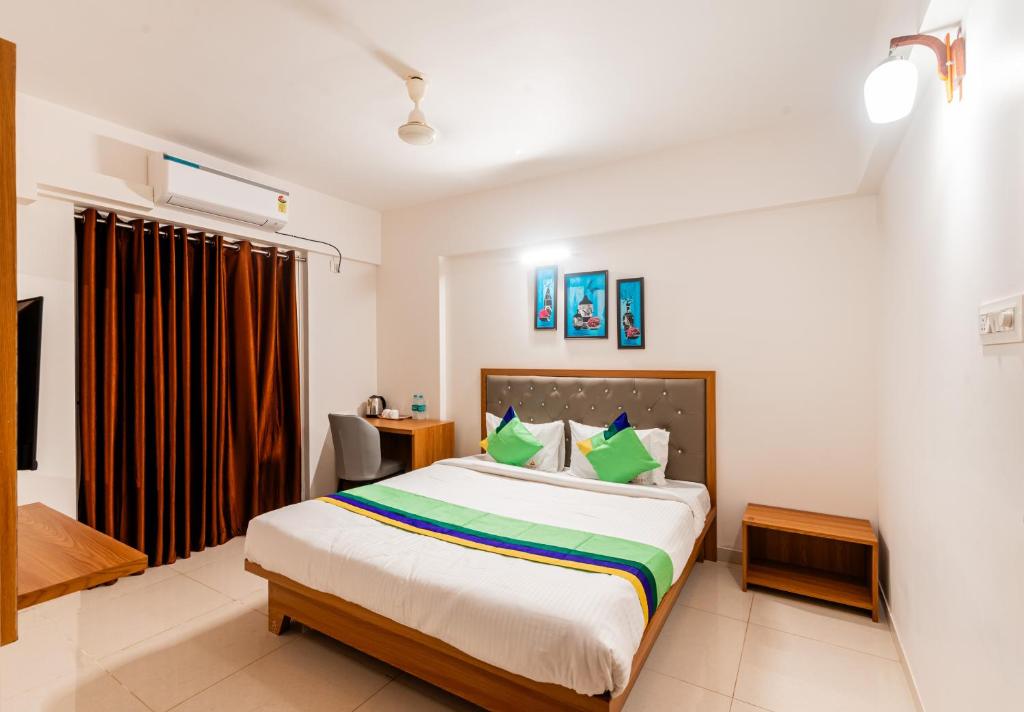 1 dormitorio con 1 cama grande con almohadas verdes en Treebo Trend Landmark en Pune