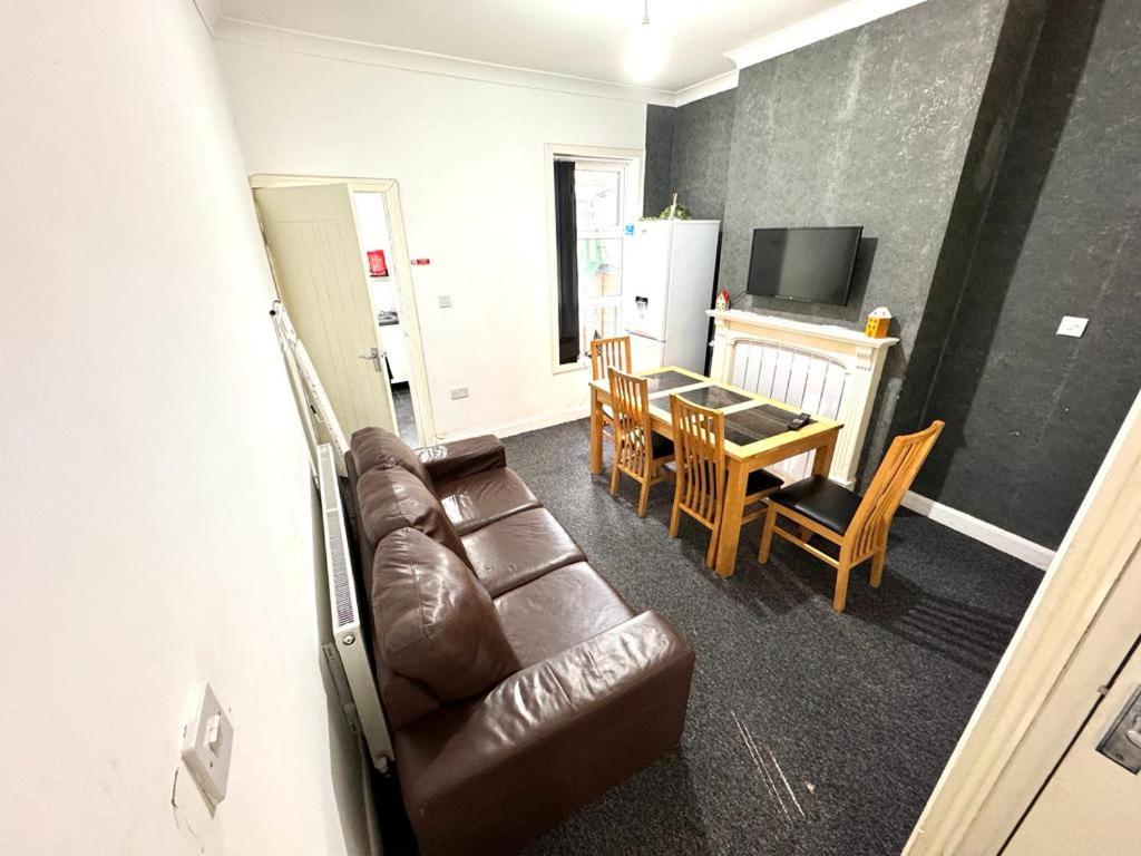 ein Wohnzimmer mit einem braunen Ledersofa und einem Tisch in der Unterkunft Three Rose Manor At Warwick Road Near Birmingham Airport in Birmingham