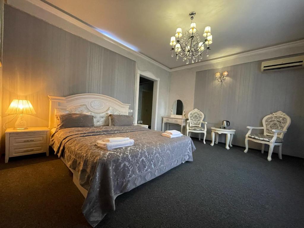 a bedroom with a large bed and chairs and a chandelier at Київські Ночі in Kyiv