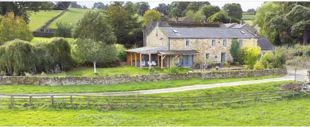 a large stone house in a field with a fence at Rookery barn in the outskirts of darley in Harrogate