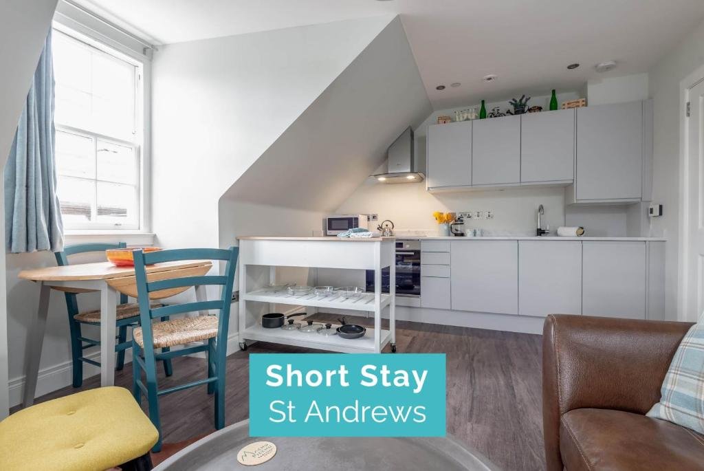 een keuken met witte kasten en een tafel en stoelen bij Luxury Penthouse Apartment on South Street in St Andrews
