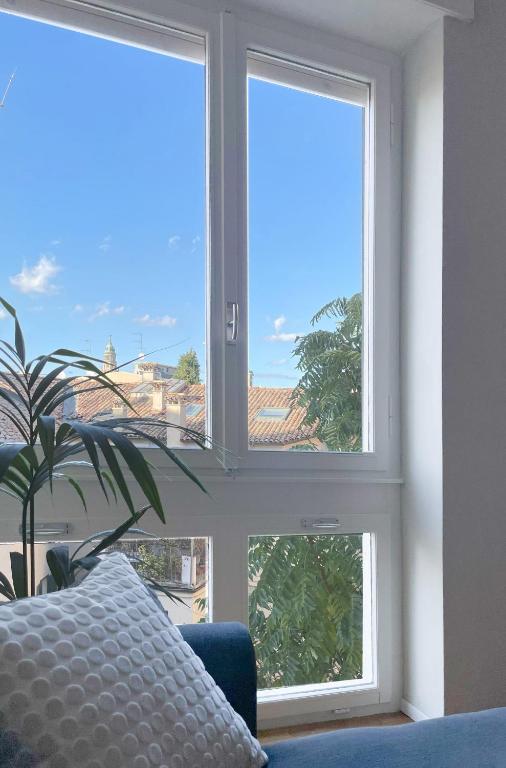 two windows in a room with a pillow and a plant at ALBORGOCOLLEGIOMARIALUIGIA in Parma