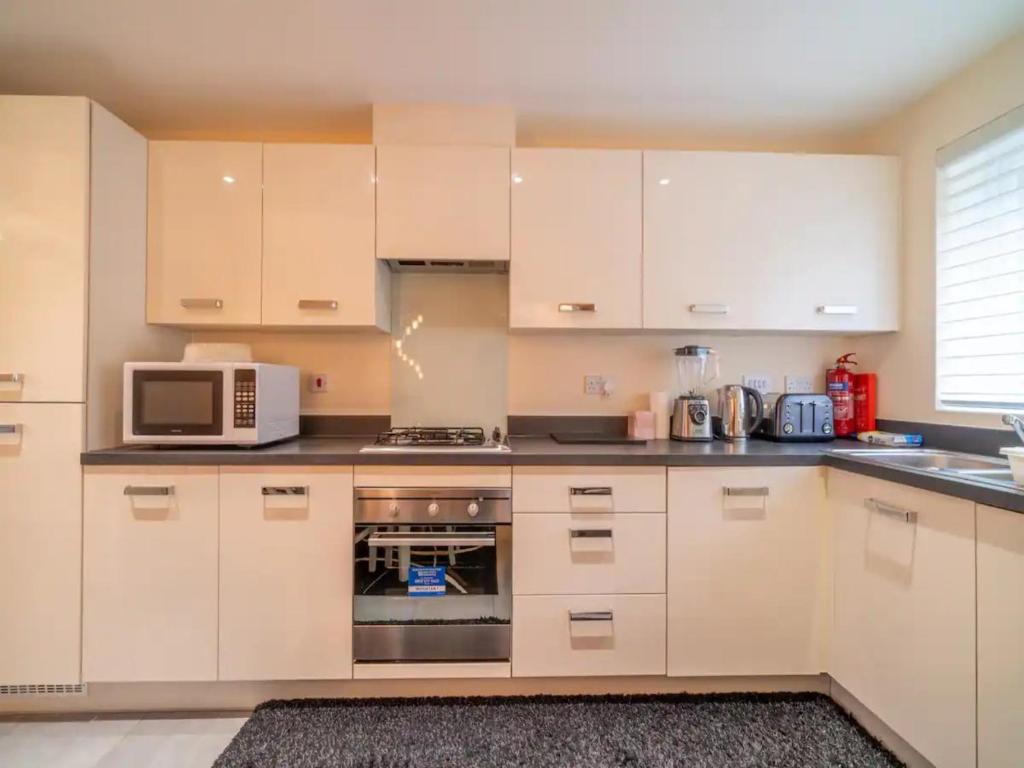 a kitchen with white cabinets and a microwave at Pass the Keys Stylish 4 bedroom home in Nottingham