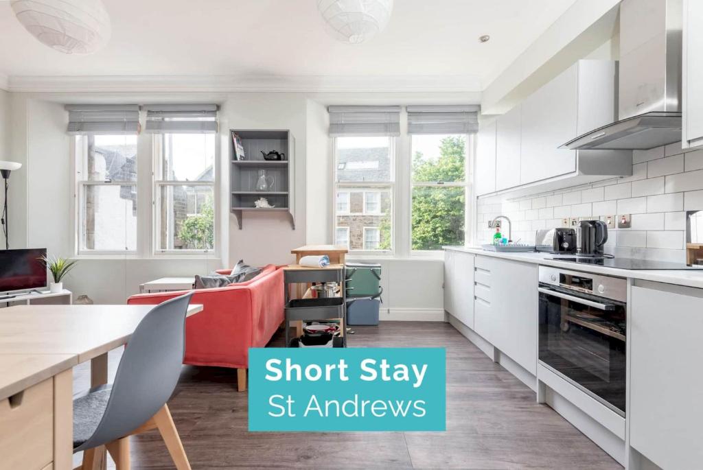 a kitchen with a red couch in a white kitchen at Stylish Apartment - Sleeps 4 - South Street St Andrews in St. Andrews