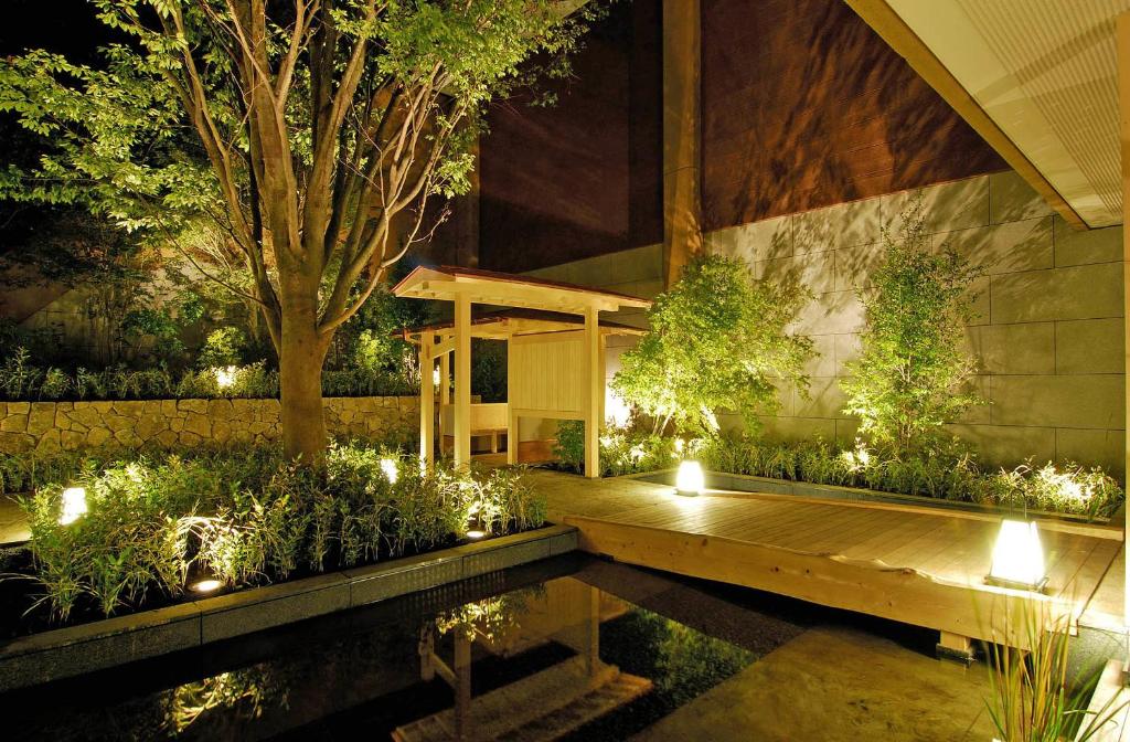 einen Garten mit einer Holzterrasse und einem Teich mit Lichtern in der Unterkunft Hakone Tokinoshizuku in Hakone