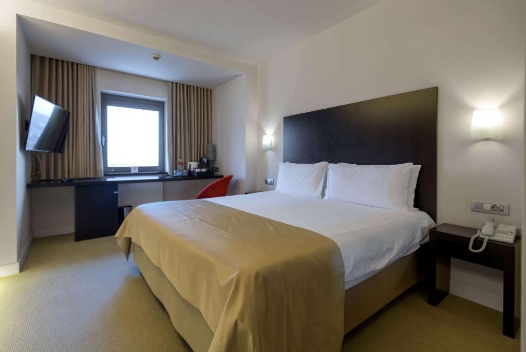a hotel room with a large bed and a television at Ramada Plaza by Wyndham Bucharest Convention Center in Bucharest