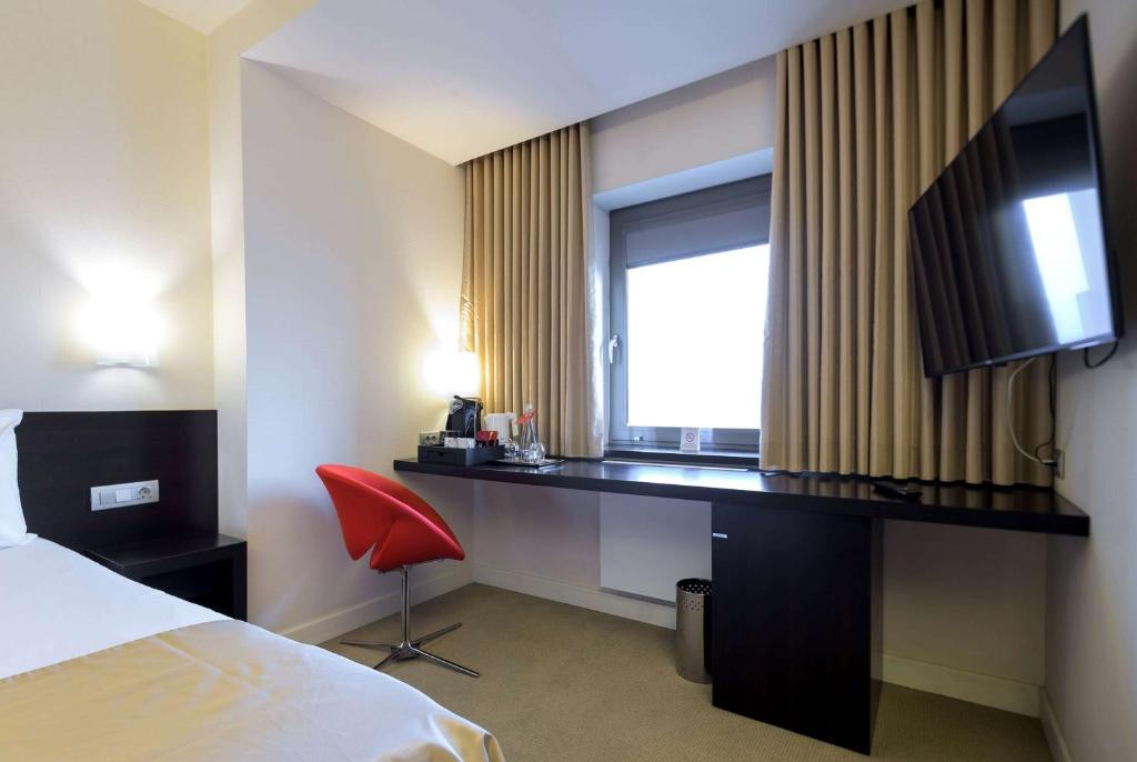 a hotel room with a desk and a window at Ramada Plaza by Wyndham Bucharest Convention Center in Bucharest