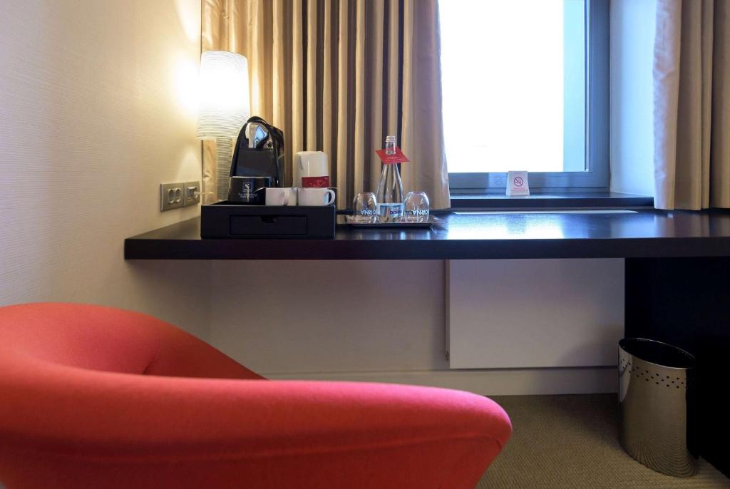 a desk with a red chair next to a room at Ramada Plaza by Wyndham Bucharest Convention Center in Bucharest