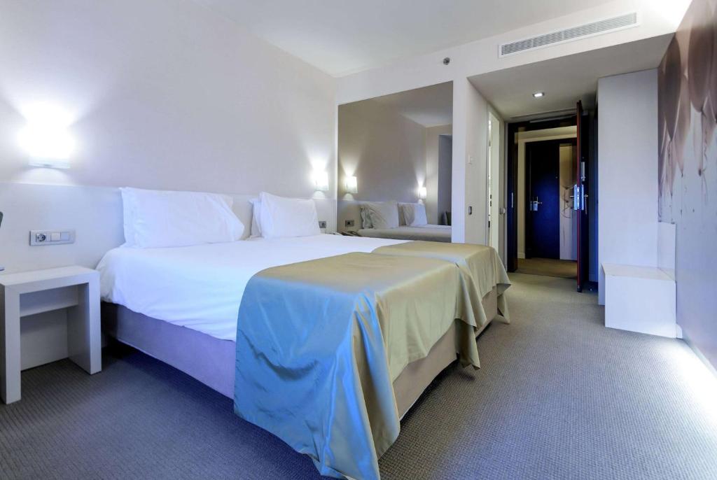 a hotel room with a large white bed and a hallway at Ramada Plaza by Wyndham Bucharest Convention Center in Bucharest