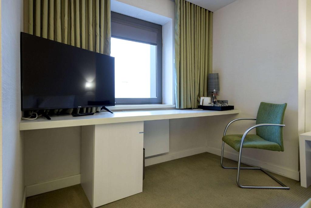 a desk with a television and a chair in a room at Ramada Plaza by Wyndham Bucharest Convention Center in Bucharest