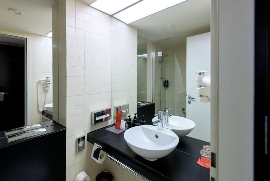 a bathroom with two sinks and a mirror at Ramada Plaza by Wyndham Bucharest Convention Center in Bucharest