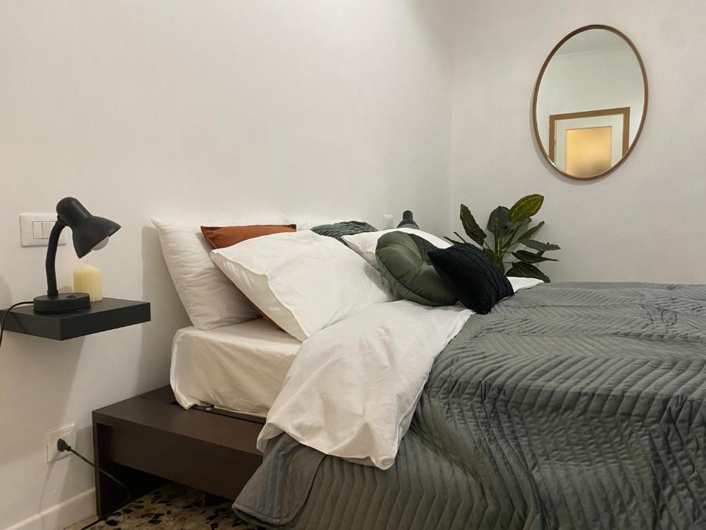 a bedroom with a bed with pillows and a mirror at Short Stay Pavia nuovo in città in Pavia