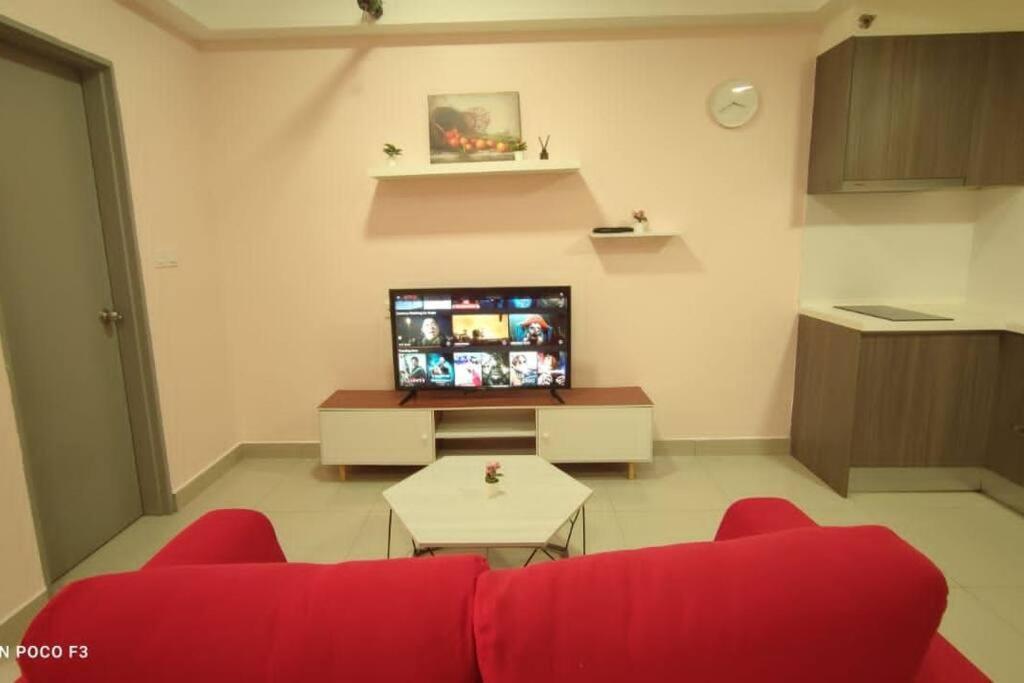 ein Wohnzimmer mit einem roten Sofa und einem TV in der Unterkunft HB1511-Cyberjaya-Netflix-Wifi-Parking-Pool , 3089 in Cyberjaya