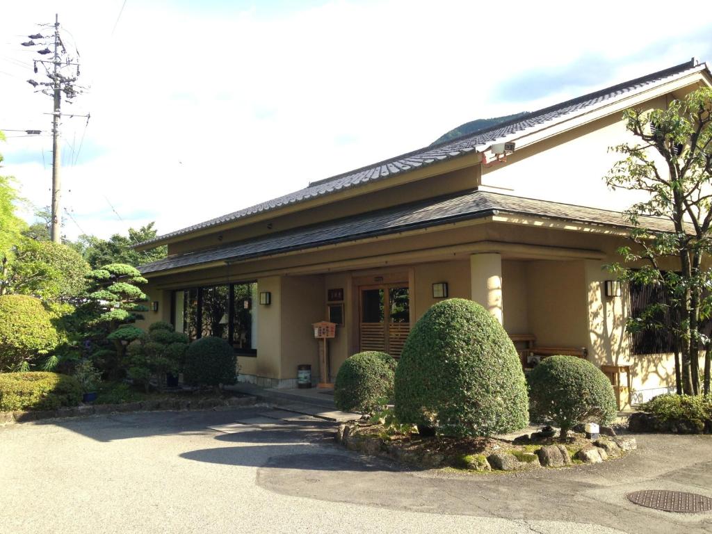 una casa con arbustos delante de ella en Kawakamiya Kasuitei en Gero