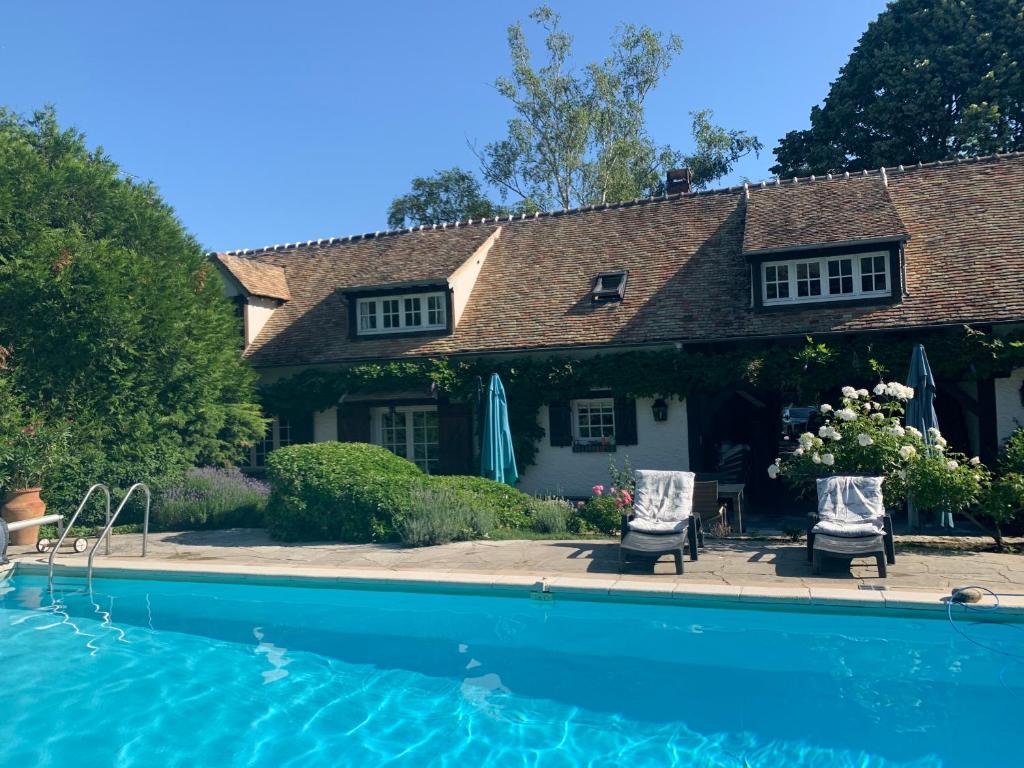 une maison avec une piscine et deux chaises dans l'établissement ENOLAND La maison du bonheur, à Bourdonné