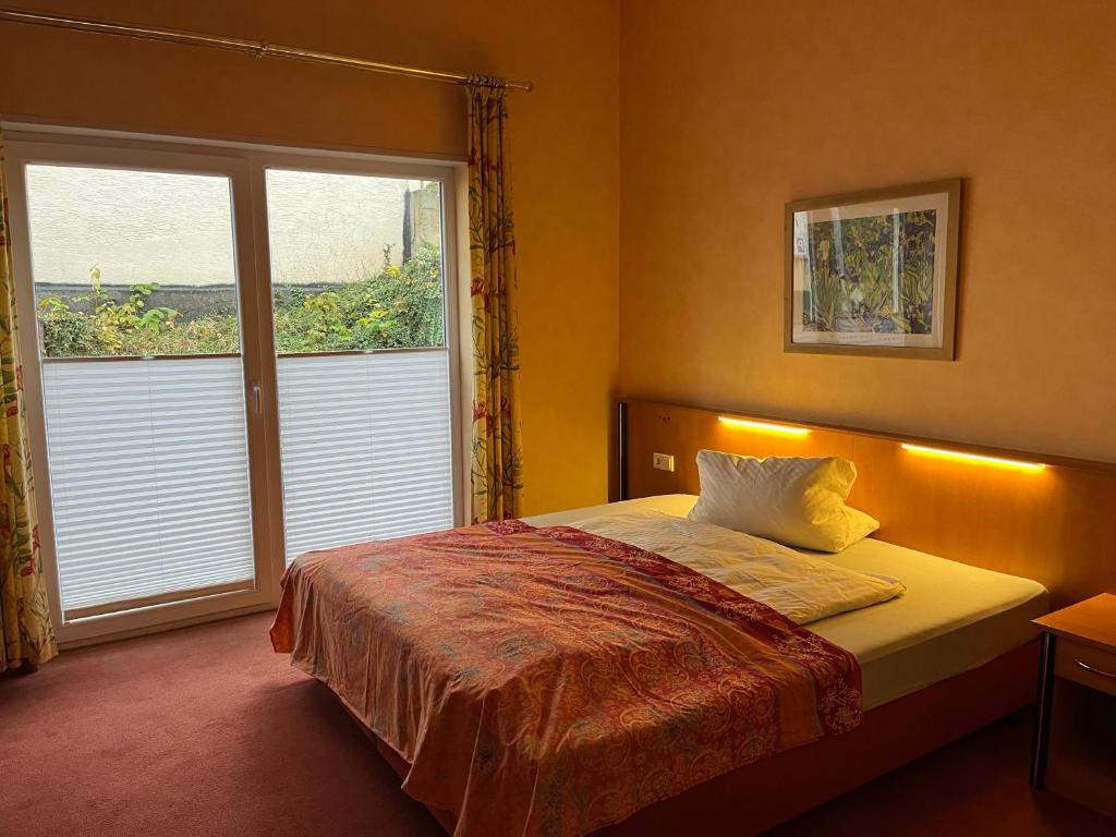 a bedroom with a bed and a large window at Landhotel Ritter-Post in Angelbachtal