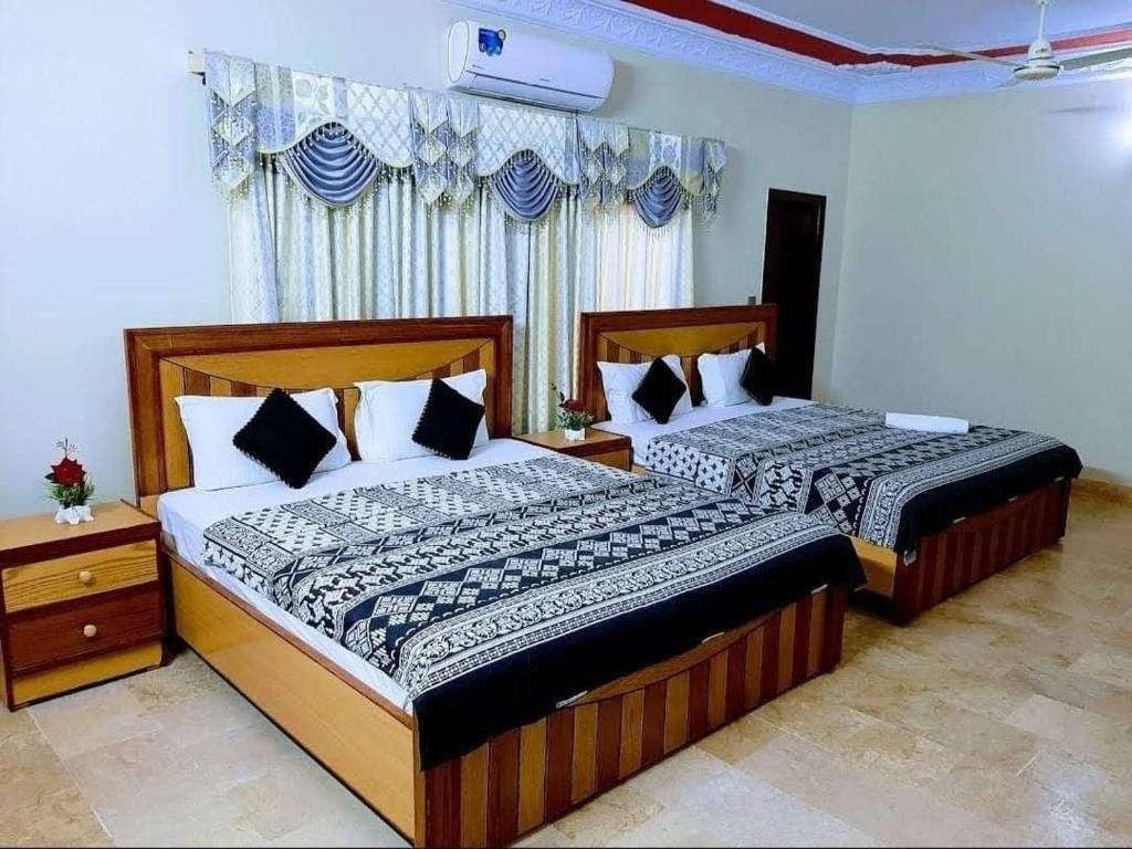 two beds in a hotel room withskirts at Galaxy Inn Guest House in Karachi