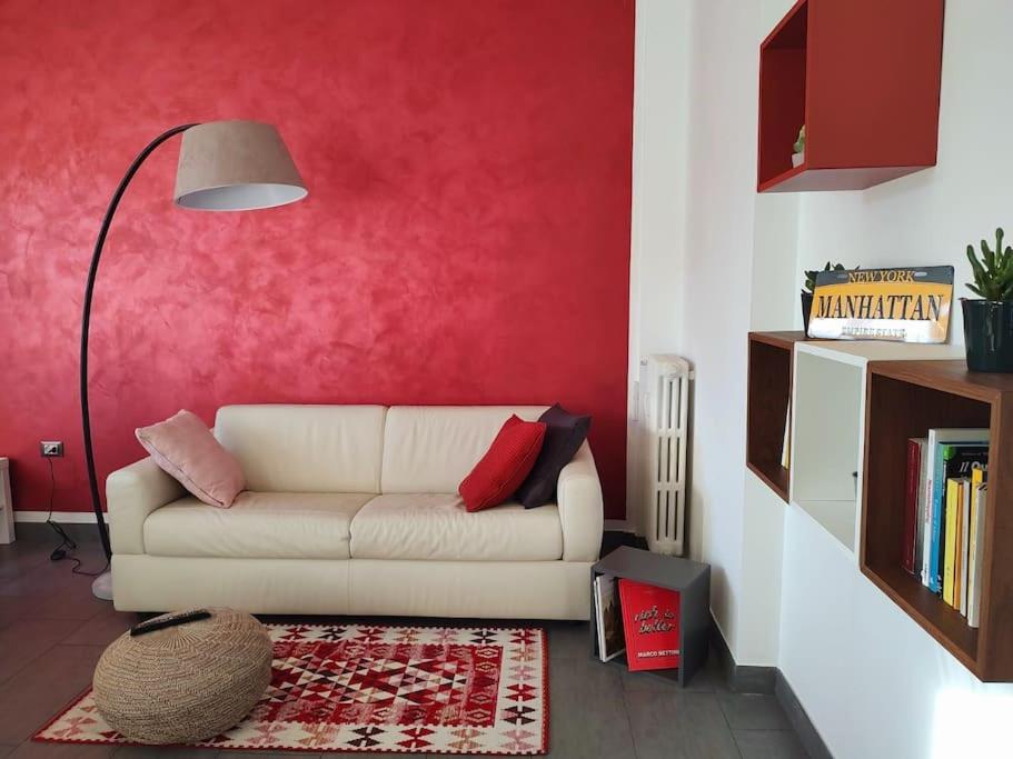 ein Wohnzimmer mit einem weißen Sofa und einer roten Wand in der Unterkunft Bilocale luminoso e accogliente zona Marche in Mailand