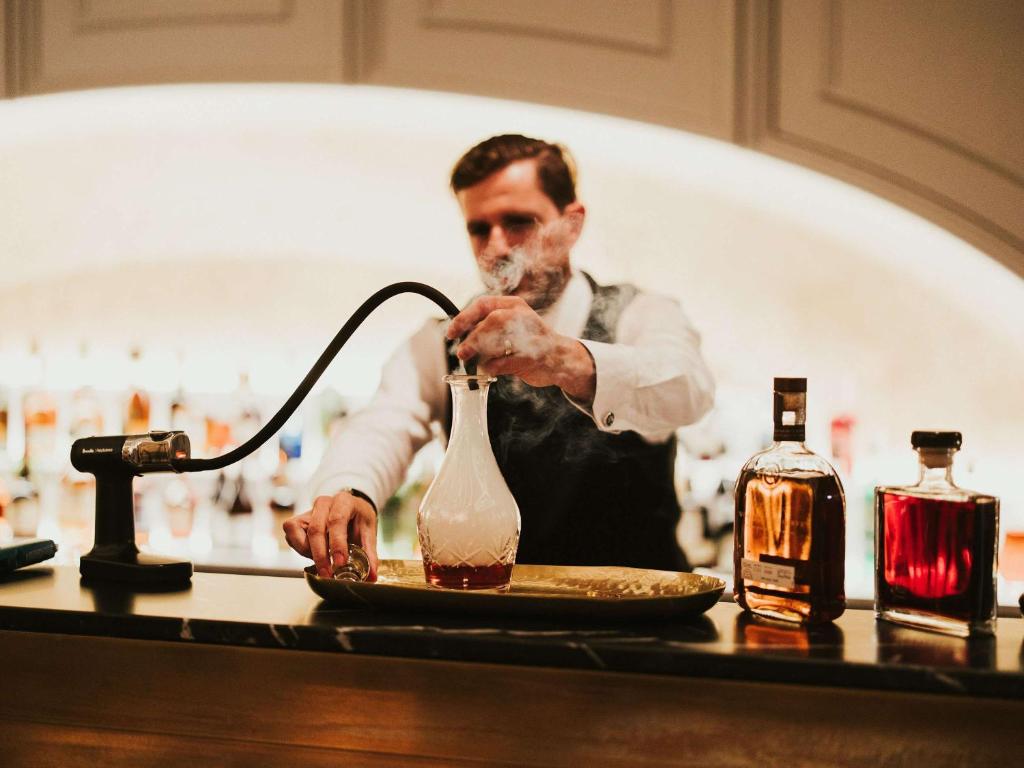 a man in a kitchen preparing a drink at The Playford Adelaide - MGallery by Sofitel in Adelaide