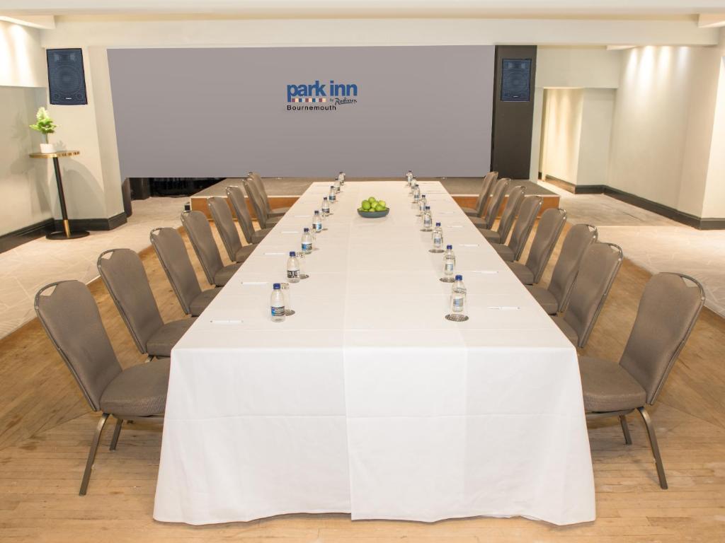 a long table in a room with chairs and a screen at Park Inn by Radisson Bournemouth in Bournemouth