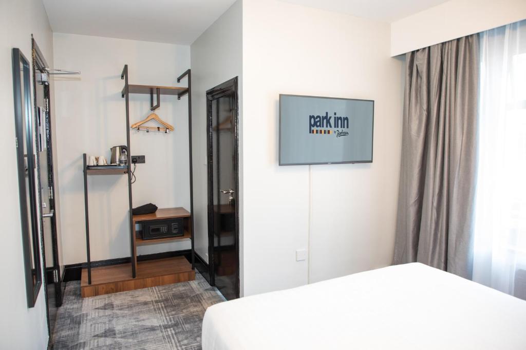 a bedroom with a white bed and a mirror at Park Inn by Radisson Bournemouth in Bournemouth