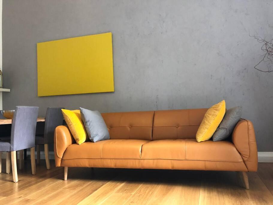 a living room with a brown couch with yellow pillows at Stylish & Tranquil in Berlin
