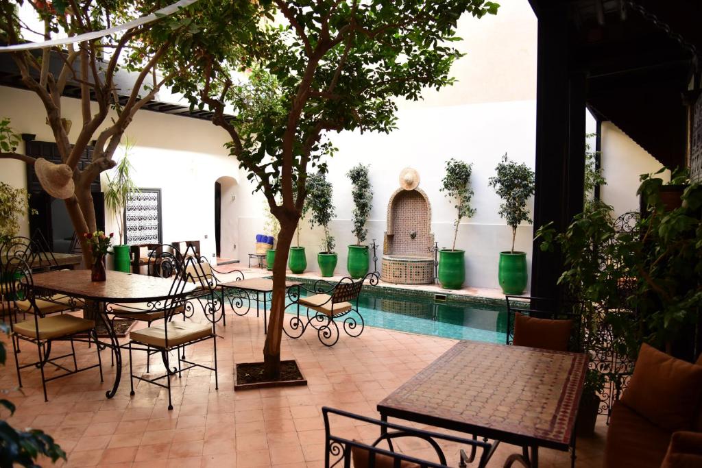 een patio met tafels en stoelen en een zwembad bij Riad Du Petit Prince in Marrakesh