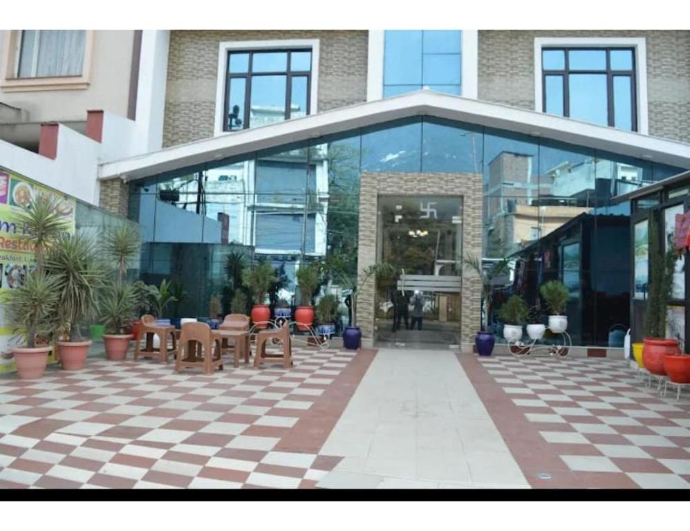 un grand bâtiment en verre avec des tables et des chaises dans l'établissement Hotel Om Karan Katra, à Katra