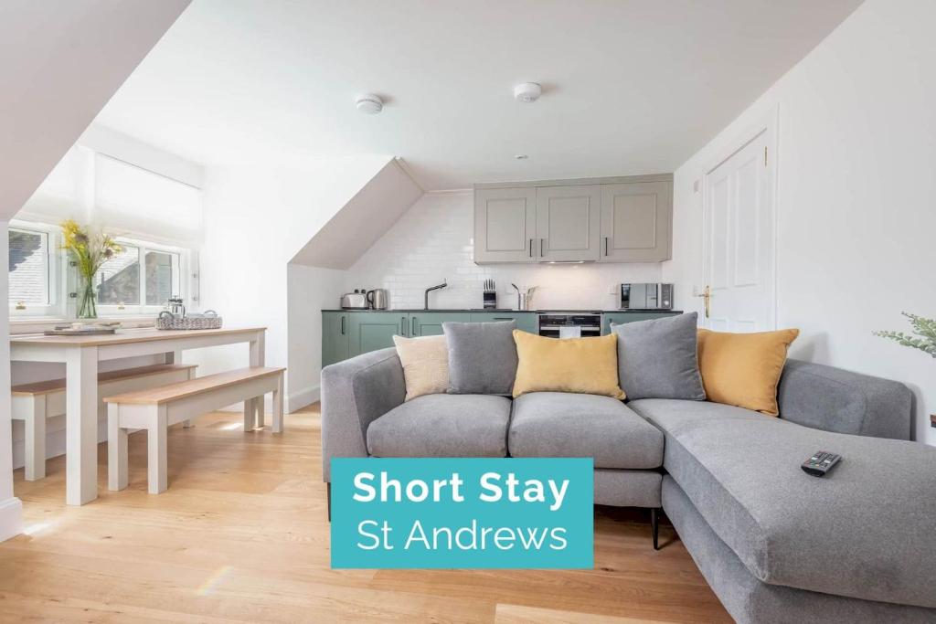 ein Wohnzimmer mit einem Sofa und einer Küche in der Unterkunft Skye Sands - Balgove Penthouse Residence - St Andrews in St Andrews