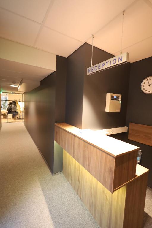 Stay Vilnius Hotel — A reception desk in a office with a clock on the wall